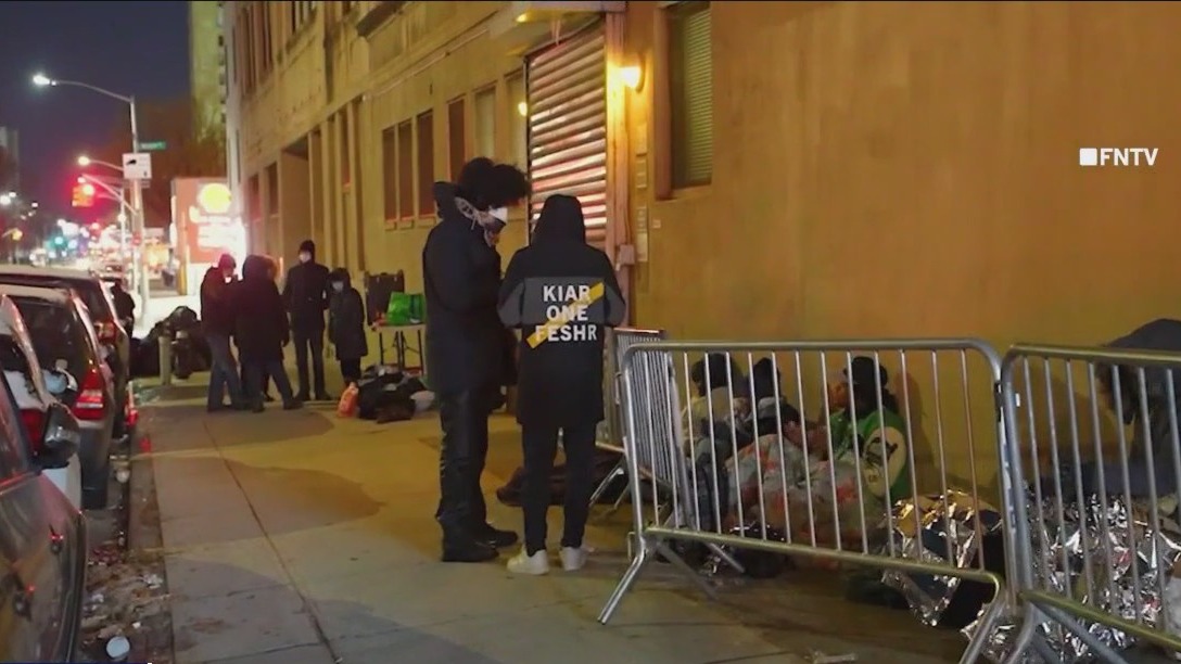 Migrants line up to receive shelter, services