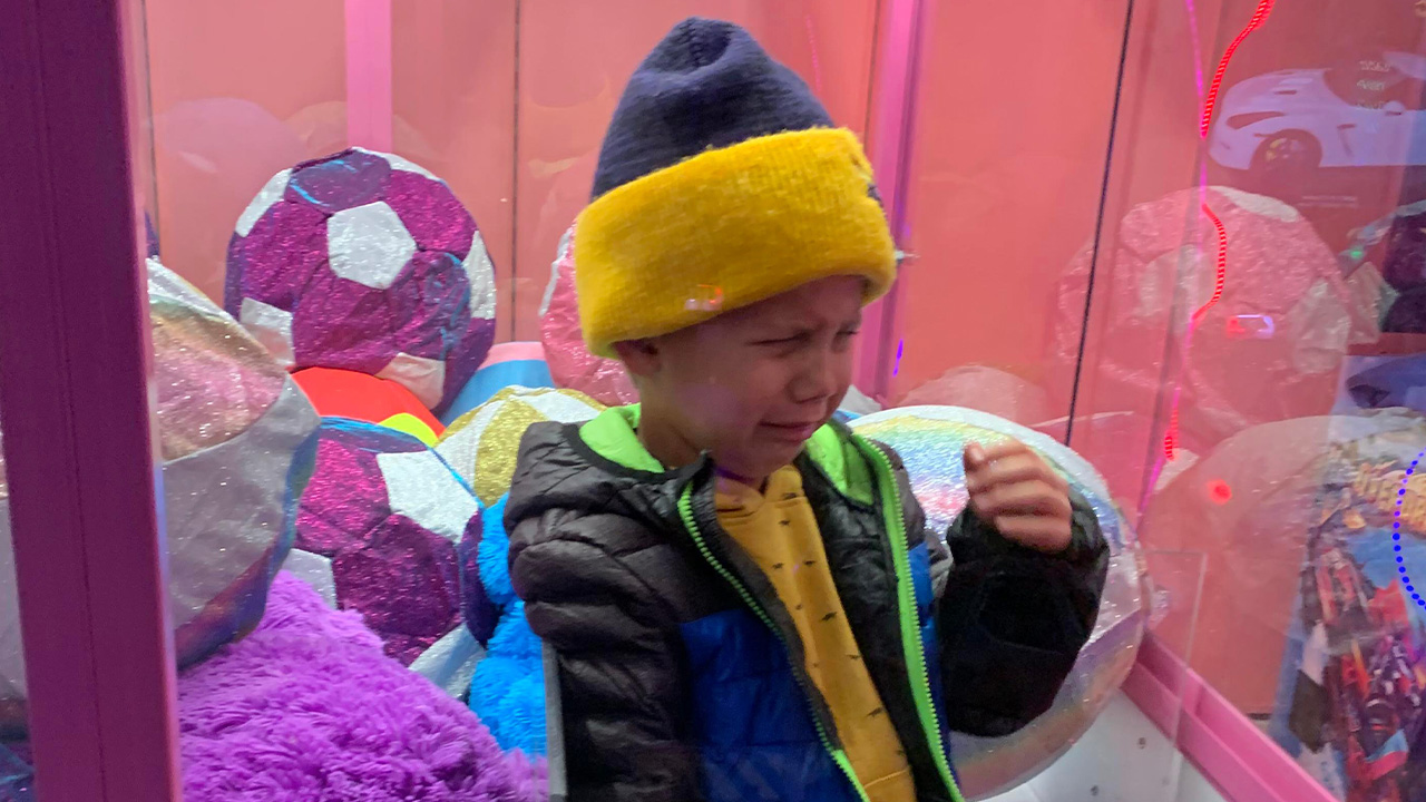 Child, frustrated with game, gets stuck in claw machine